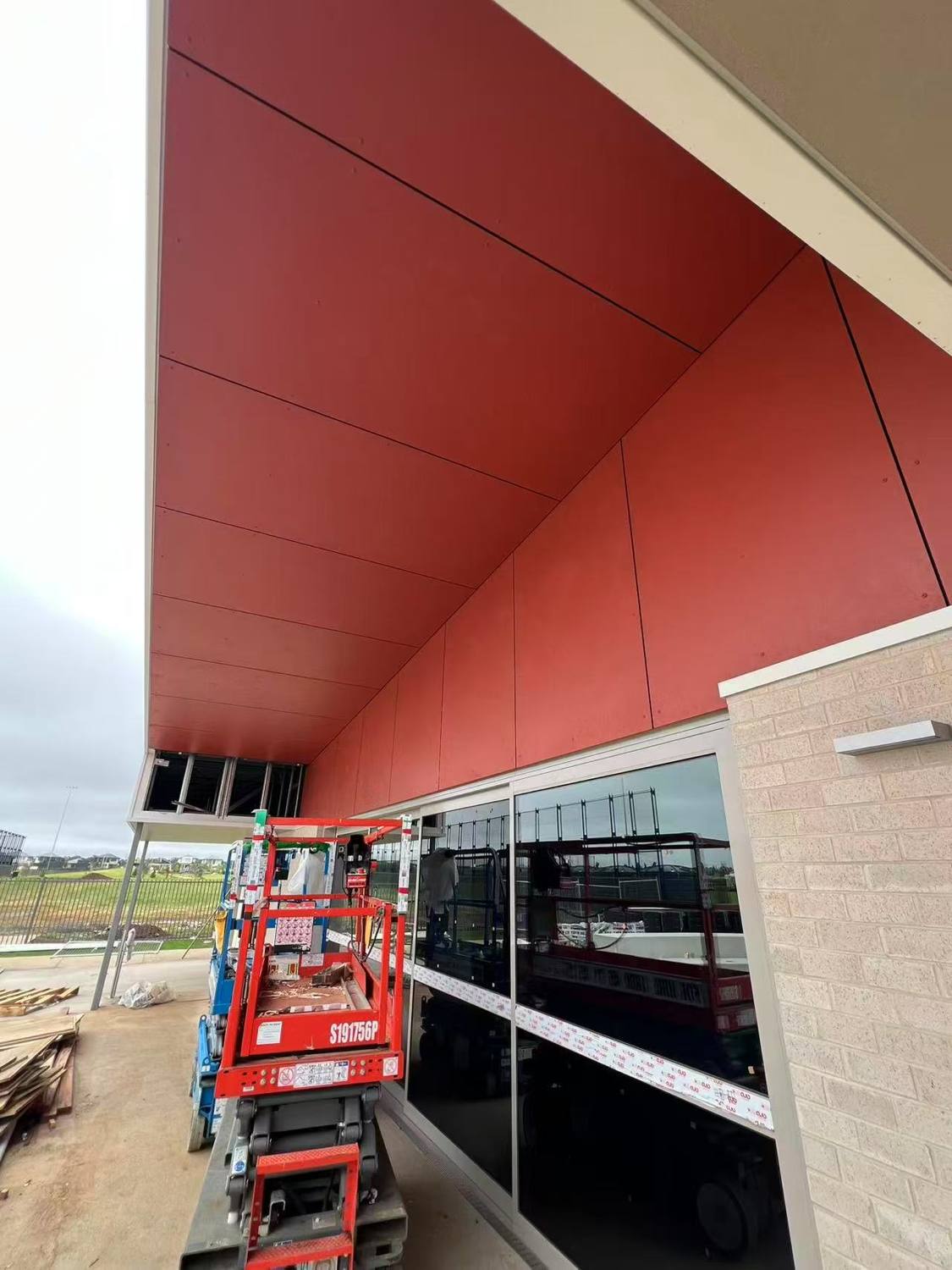 Red fibre cement soffit and wall panels over an entry with glazing