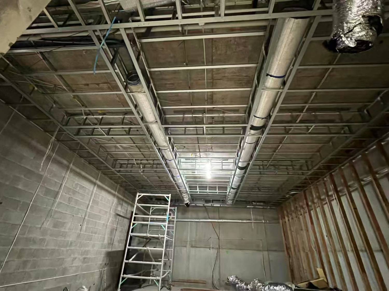 Steel ceiling grid and wall framing in a basement tenancy with ductwork above