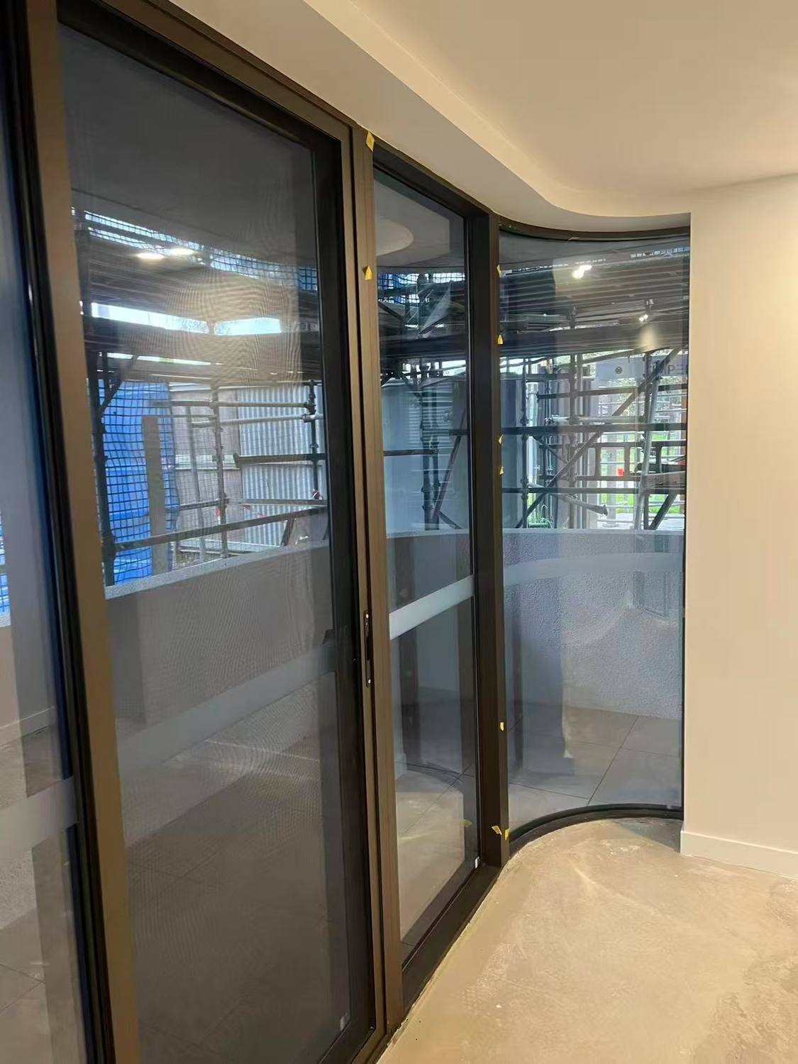 Bronze-framed sliding glass doors with a curved glazed corner and curved ceiling