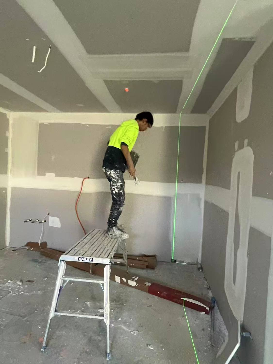 Plasterer setting joints on a ceiling with a laser level